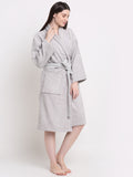 A woman wearing a silver 100% cotton bathrobe with a waist belt and front pocket