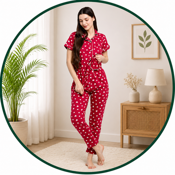 Woman wearing red polka dot pajamas in a cozy room with a plant and lamp.
