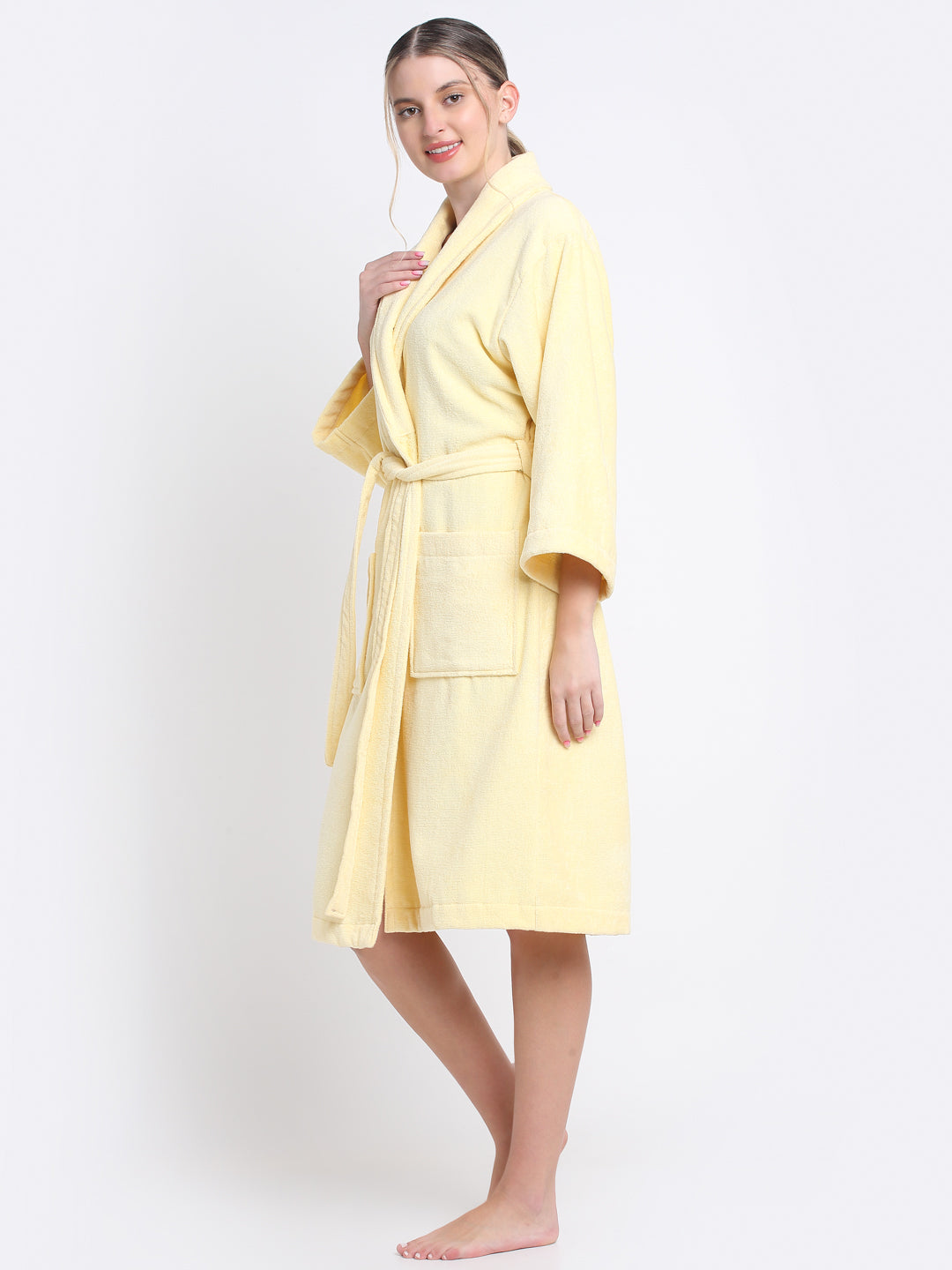 A Woman smiling and wearing a royal yellow 100% cotton bathrobe with a waist belt and front pockets.