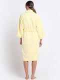 Back view of a woman wearing a royal yellow bathrobe with a waist belt