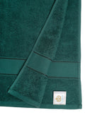 Close-up of a folded dark green towel with a label. Creeva