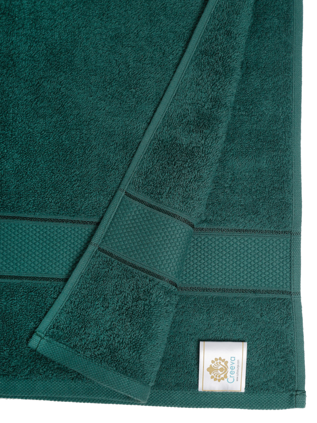Close-up of a folded dark green towel with a label. Creeva
