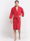 A person standing and modeling a crimson red 100% cotton unisex bathrobe with a front pocket and a tie belt.