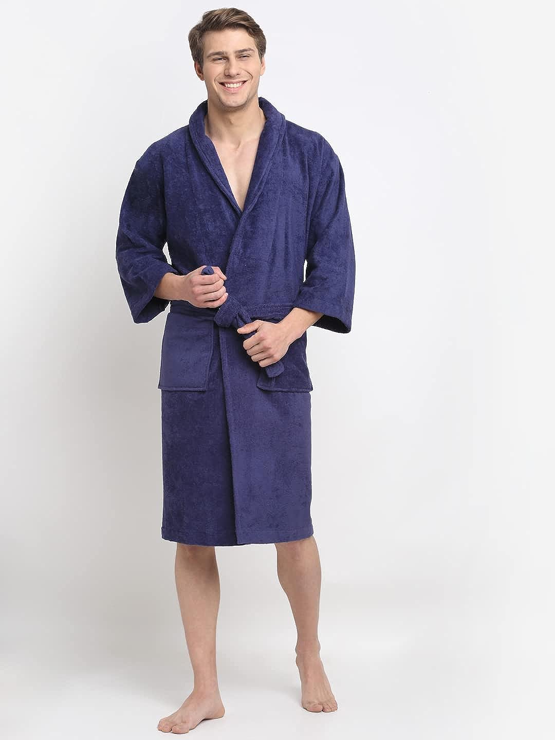 A person standing and smiling, wearing a navy blue 100% cotton unisex bathrobe with a belt tied around the waist.