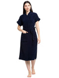 A woman standing and posing in a navy blue terry bathrobe with a belt tied around her waist.