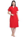 A woman standing and wearing a bold red terry bathrobe with a V-neck and long sleeves.