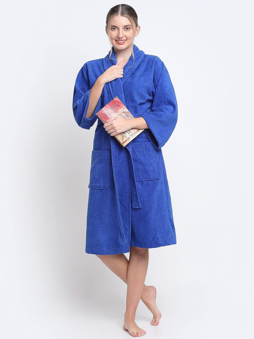 A person standing and wearing a royal blue, 100% cotton unisex bathrobe with a belt tied around the waist.