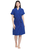 A woman standing, wearing a soft royal blue terry bathrobe with a V-neck and a tie belt.
