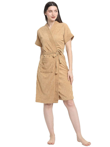 A woman standing and wearing a rust terry bathrobe with a belt tied around the waist.