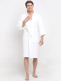 A person standing and smiling, wearing a white 100% cotton unisex bathrobe with a belt tied around the waist.