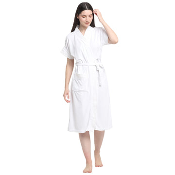 A woman wearing a classic white terry cloth bathrobe with a belt tied around the waist, standing on a white background.