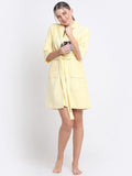 A woman wearing a royal yellow 100% cotton bathrobe with a waist belt and front pockets.