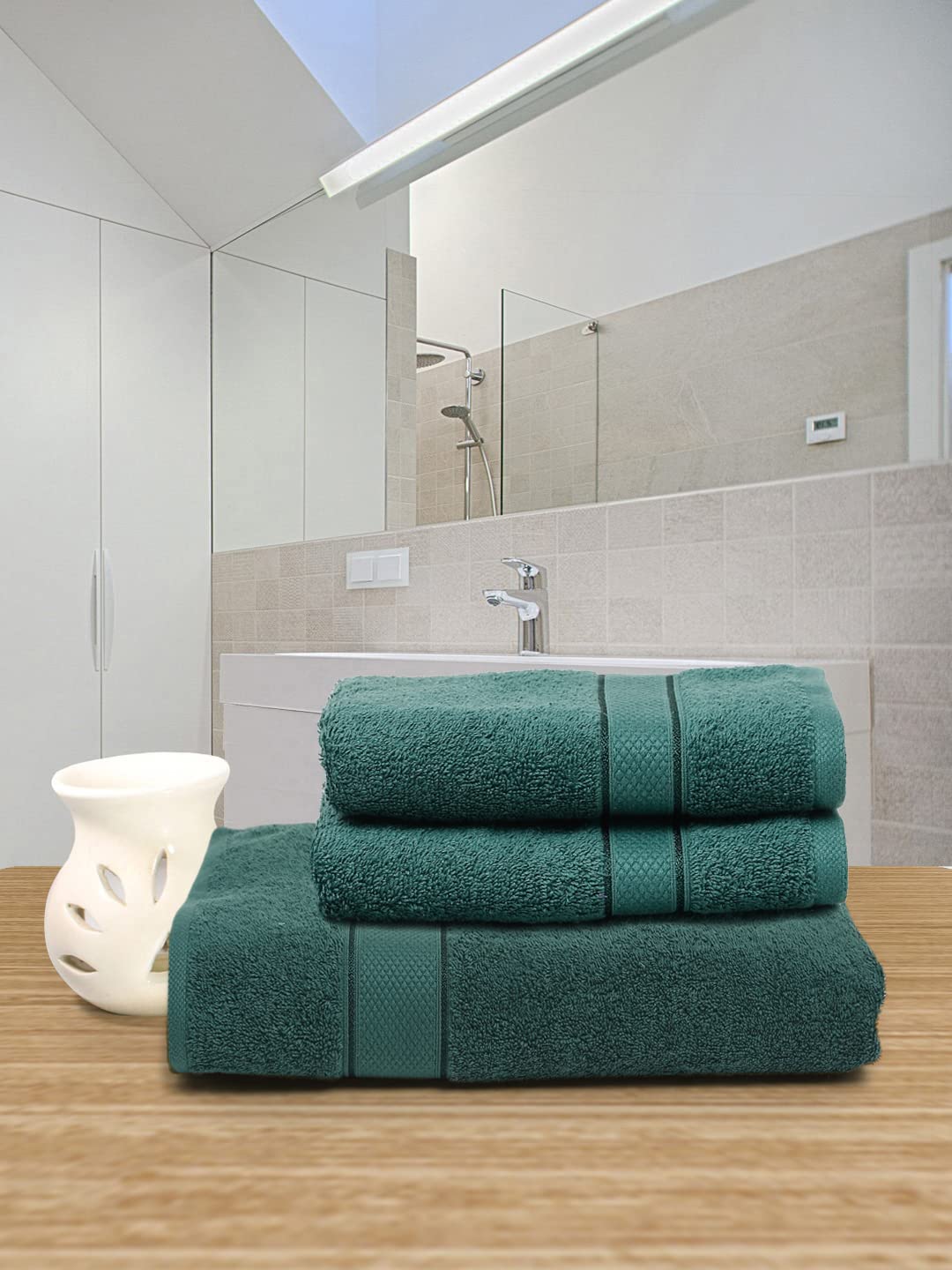 A stack of three teal bath towels on a white background.